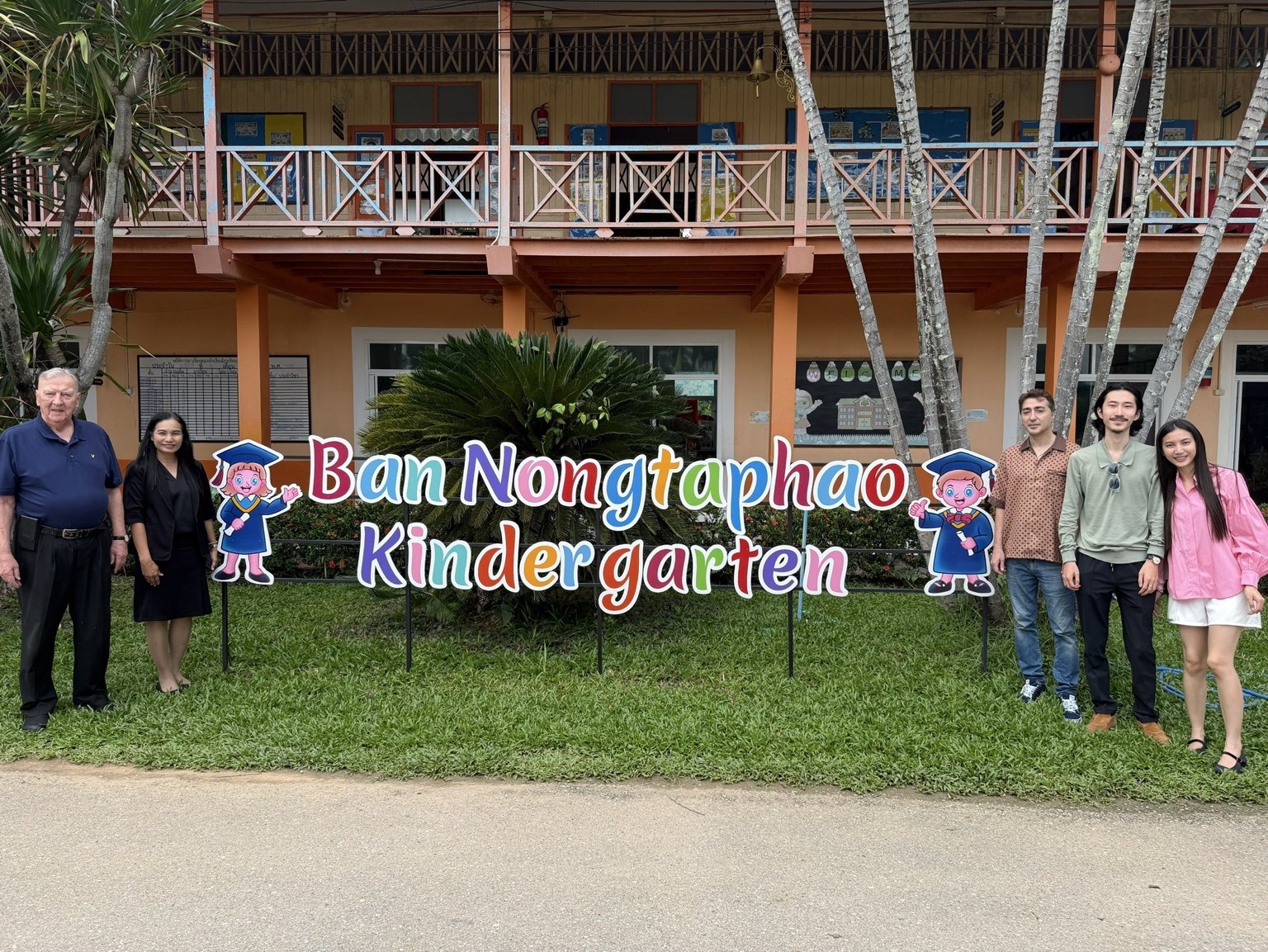 A group photograph outside Ban Nong Taphao Kindergarten during the visit.